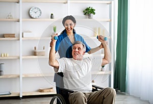 Post-stroke rehabilitation. Female physiotherapist helping elderly male patient in wheelchair to make exercises at home photo