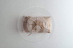 Postal package wrapped in craft paper on white background