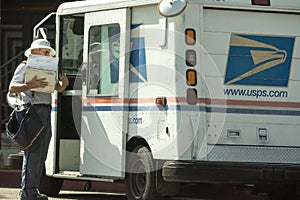 Postal worker with package at truck