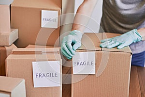 Postal worker putting a fragile label on a cardboard box