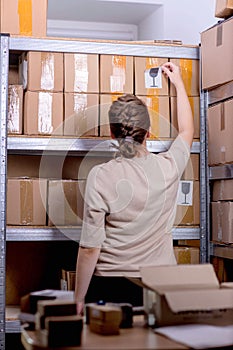 Postal worker sticking fragile or glass mark to parcel box at post office