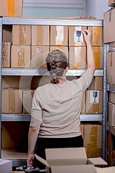 Postal worker sticking fragile or glass mark to parcel box at post office