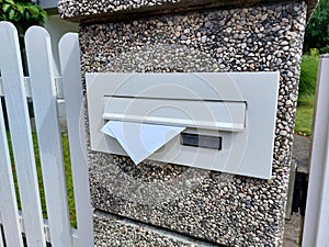 postbox on white fence. Letters in mailbox