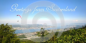 Postcard with a beautiful view in sunny summer weather over yachts, sailboats and paragliding sports on Lake Zurich