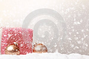 Postcard Merry Christmas. Gift box and balls baublse on snow and defocused snowfall photo