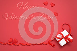 Postcard with space for text. Valentine`s day, a gift with a red ribbon and hearts, on a red background. mockup