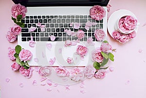 Postcard template. The laptop keyboard is strewn with flowers, a white cup pink background. Valentine`s Day. Women`s Day. Festiv