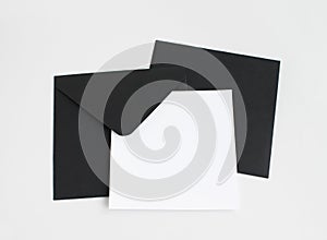 Two black envelopes with white paper on grey background. Postcard template.