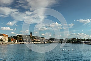 Postcard view of famous Vysehrad standing on a rock and Rasin Embankment,Prague,Czech republic.Riverfront colorful buildings,boats