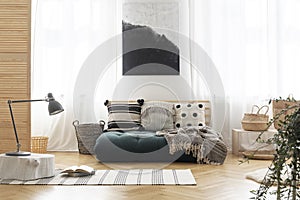 Poster above green futon with patterned pillows photo