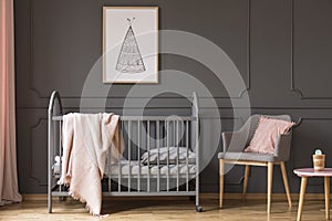 Poster above kid`s bed with blanket next to grey armchair with p