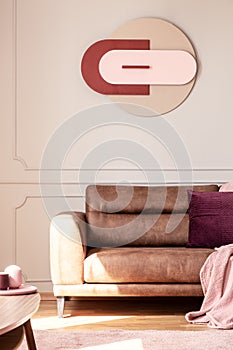 Poster above leather settee with purple cushion in modern living room interior