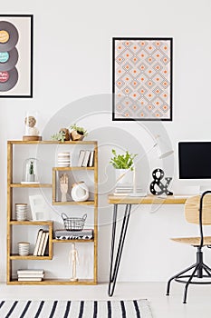 Poster above wooden desk with plant and desktop computer in home