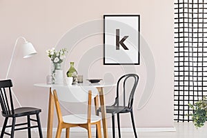 Poster on pastel pink wall of sophisticated dining room interior with round table photo