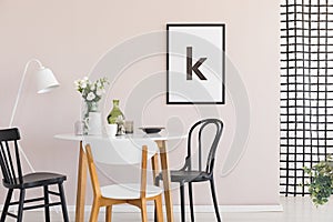 Poster on pastel pink wall of sophisticated dining room interior with round table