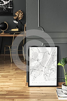 Poster and plant on wooden floor in grey workspace interior with