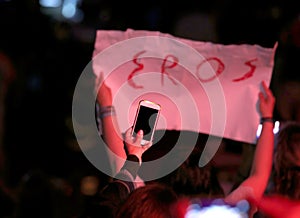 Poster with text EROS during a live concert