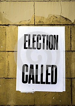 Poster with words Election Called in bold text pasted onto dirty stained yellow brick wall photo
