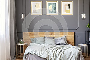 Posters on grey wall with molding above bed with wooden bedhead