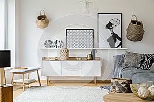 Posters and plates above wooden cupboard in boho living room int