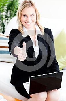 Postive businesswoman with thumb up using a laptop photo