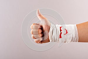 Postive gesture of thumbs up by wrapped hand with smiling face photo