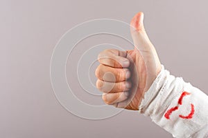postive gesture of thumbs up by a wrapped hand with a smiling face photo