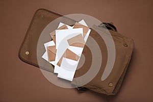 Postman bag with mails on brown background, top view