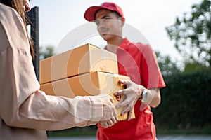 The postman delivered the parcel home with a smile and a happy face. Young Asian woman taking a box from the postman at the door