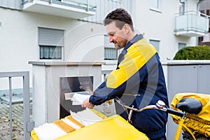 Postman delivering letters to mailbox of recipient photo