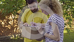 The postman delivers a parcel for a young woman