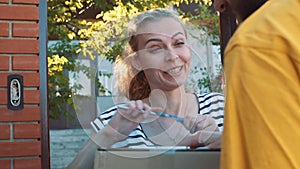 The postman delivers a parcel for a young woman