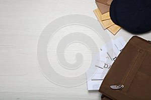 Postman hat, bag, newspapers and mails on white wooden table, flat lay. Space for text