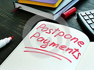 Postpone payments red memo on the page and calculator. Deferment or Forbearance concept.