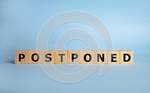 Postponed - words from wooden blocks with letters, postponed concept, top view background