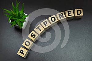 Postponed - words from wooden blocks with letters, postponed concept, top view gray background