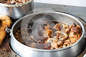 Pot of bak kut teh being cooked consisting pork and herbal soup