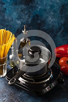 The pot with boiling water for preparing spaghetti on dark blue background. Backstage of cooking pasta. Food concept