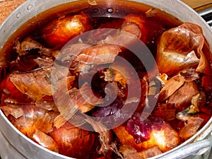 Pot with brown water from onion peels boiling Easter eggs colored by using different leaves, plants and flowers