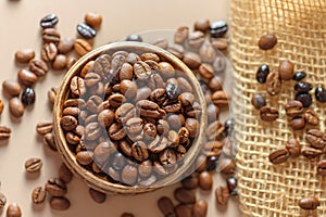A pot of coffee beans on a sacking. Roasted coffee beans are scattered on the table. A mix of different types of coffee roasting