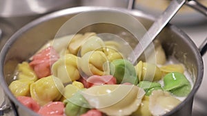 In a pot, colorful dumplings are being boiled. Preparing lunch or dinner