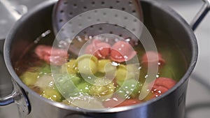 In a pot, colorful dumplings are being boiled. Preparing lunch or dinner