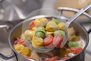 In a pot, colorful dumplings are being boiled. Preparing lunch or dinner