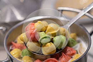 In a pot, colorful dumplings are being boiled. Preparing lunch or dinner