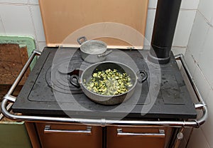 Pot with cooked zucchini in the ancient stove with fire lit photo