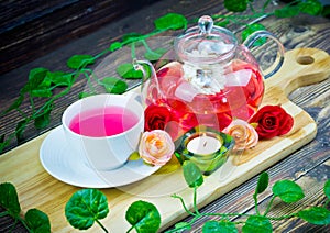 Pot and cup of Rose tea on wood background