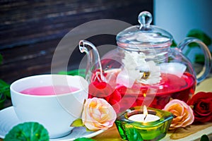 Pot and cup of Rose tea on wood background