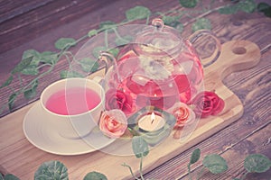 pot and cup of Rose tea on wood background