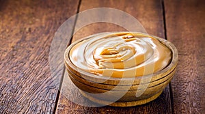 Pot of dulce de leche or homemade caramel on rustic wooden background, typical Brazilian sweet