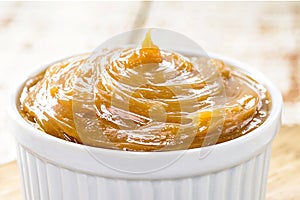 pot of dulce de leche or homemade caramel on rustic wooden background, typical Brazilian sweet